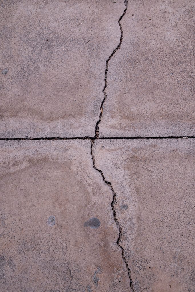 Close-up view of a cracked concrete surface showcasing natural texture and weathered appearance.
