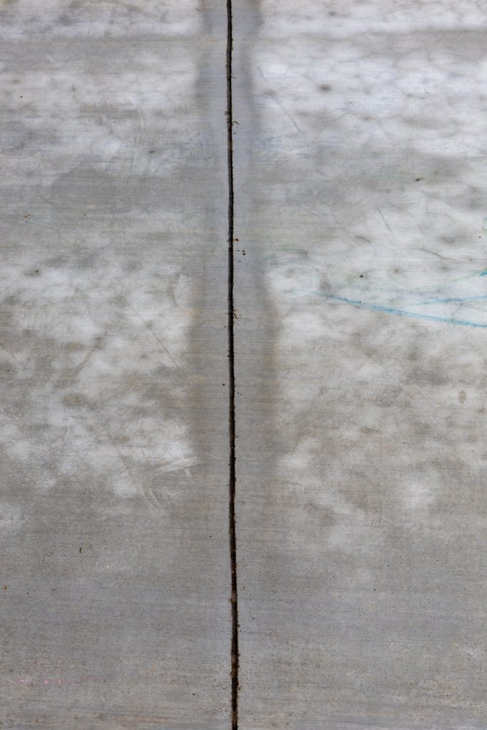 Detailed view of a cracked concrete surface, emphasizing texture and line.